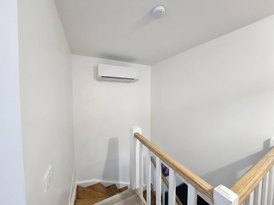 Scène extérieure sur mur orange avec unité extérieure de climatisation fixée sur support métallique