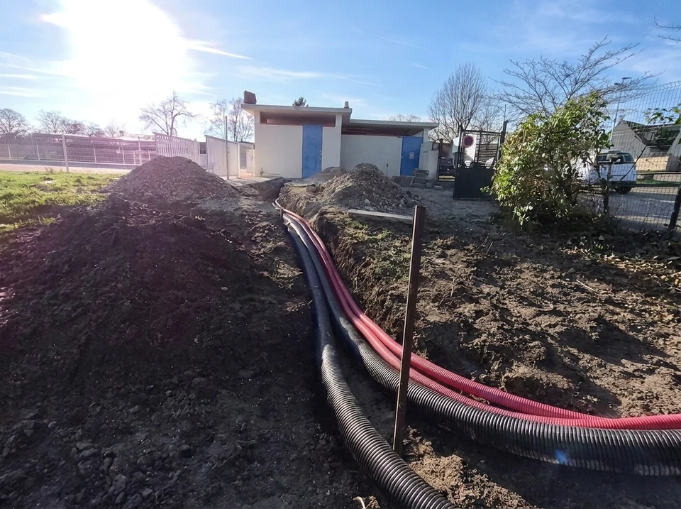 Jardin extérieur ensoleillé avec unité extérieure de pompe à chaleur air/air installée sur dalle béton contre mur enduit
